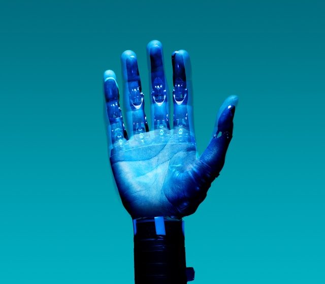 A hand is centre of the screen. It is blue and appears to have computer coding written across it in the light.